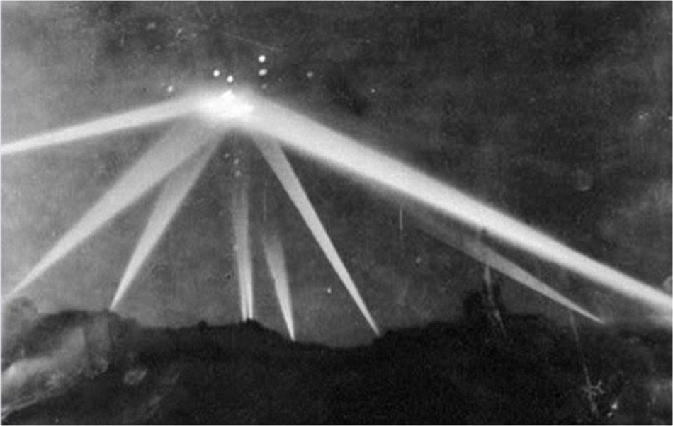 1942年2月25日，洛杉矶上空，防空探照灯照射一个不明物体。照片中的光点为防空炮弹爆炸后产生的闪光。
