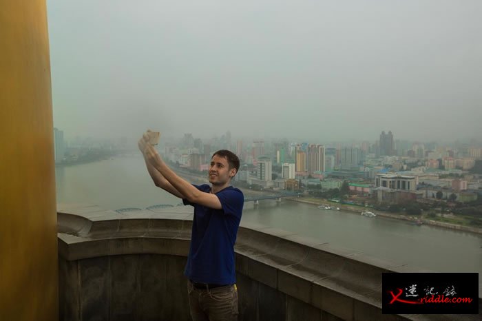 观光客雅各．奥克斯丁（Jacob Augustine）在平壤主体思想塔（Juche Tower）上自拍。 PHOTOGRAPH BY DAVID GUTTENF